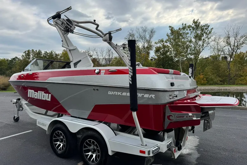 Slide: The Image of 2023 Malibu Wakesetter 20 VTX boat on trailer, red and silver design, parked outdoors. - 5