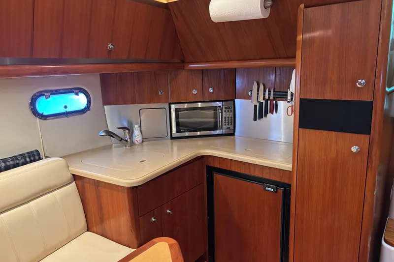 Slide: The Image of 2004 Tiara Yachts 3600 Sovran galley with wood cabinetry, microwave, and sink. - 21