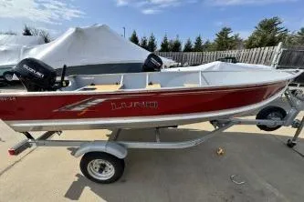 Slide: The Image of 2023 Lund SSV-14 Tiller boat on trailer, red exterior, parked outdoors. - 11
