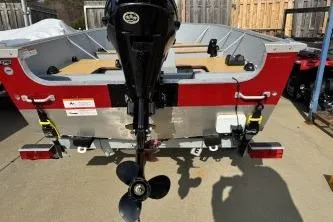 Slide: The Image of 2023 Lund SSV-14 Tiller boat, rear view with motor, parked outdoors. - 13