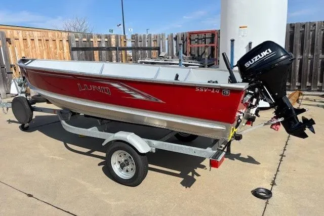 Slide: The Image of 2023 Lund SSV-14 Tiller boat with Suzuki motor on trailer, parked outdoors. - 4