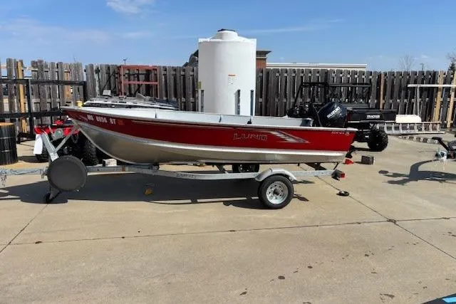 Slide: The Image of 2023 Lund SSV-14 Tiller boat on trailer, red and silver, parked outdoors. - 5