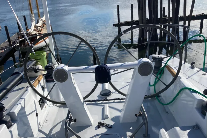 Slide: The Image of Dual steering wheels on a 1995 Tripp 47 sailboat docked by calm water. - 16