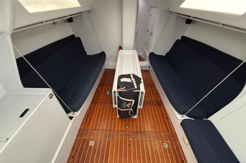Slide: The Image of Interior of a 1995 Tripp 47 sailboat with wooden flooring and navy seating. - 27