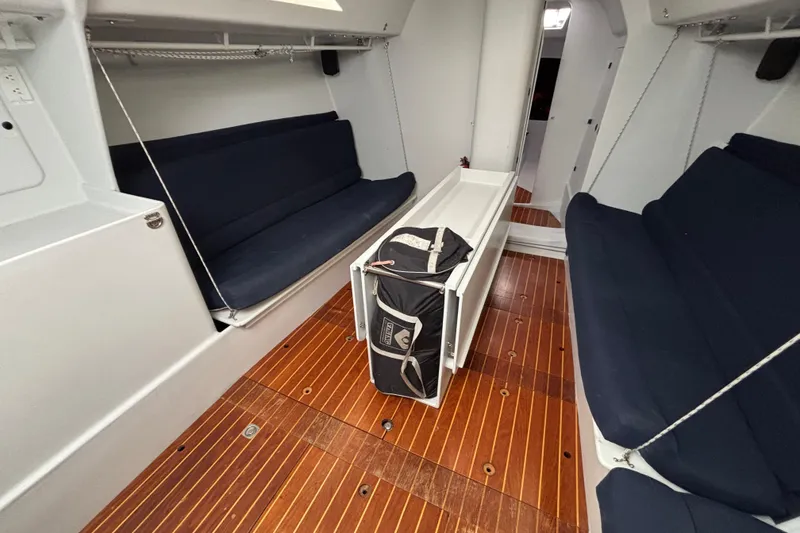 Slide: The Image of Interior of a 1995 Tripp 47 sailboat with wooden flooring and navy seating. - 28