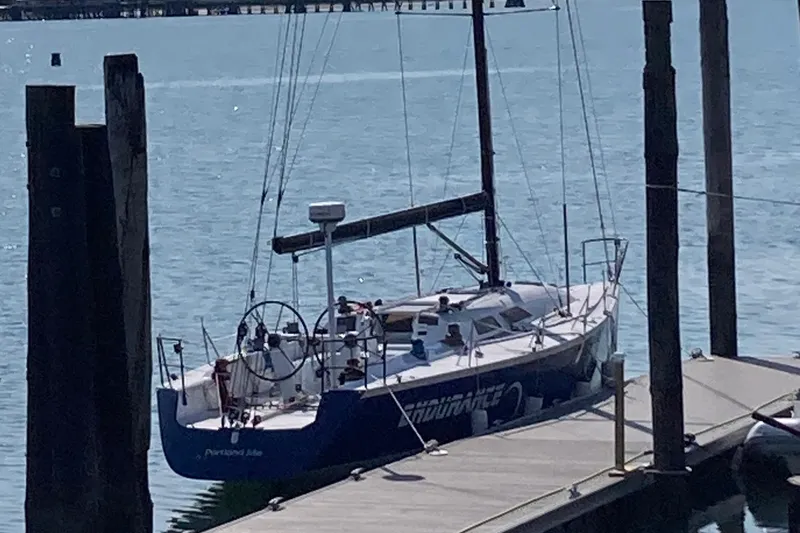 Slide: The Image of Sailboat docked at marina, Tripp 47 model, 1995, with blue hull and visible steering wheel. - 5