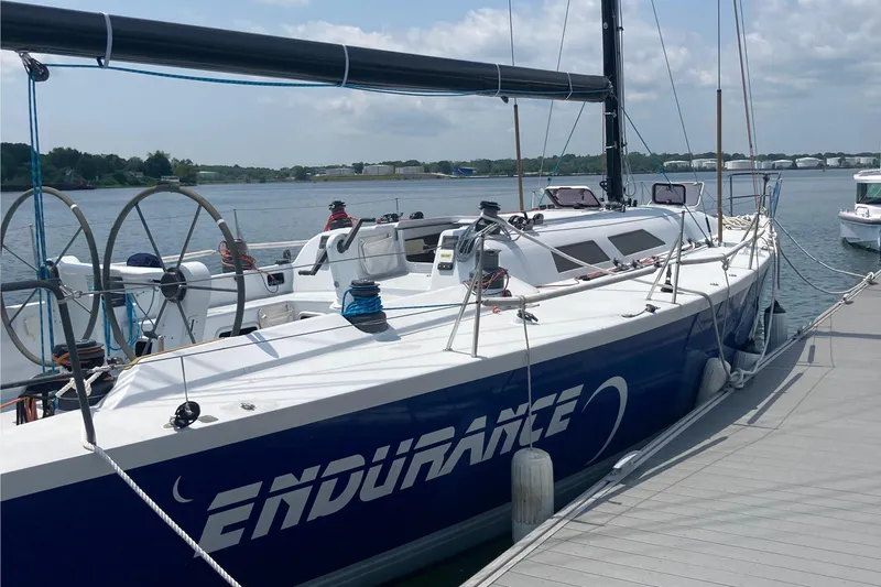 Slide: The Image of Sailboat "Endurance" docked, Tripp 47 model, 1995, with scenic waterfront background. - 6