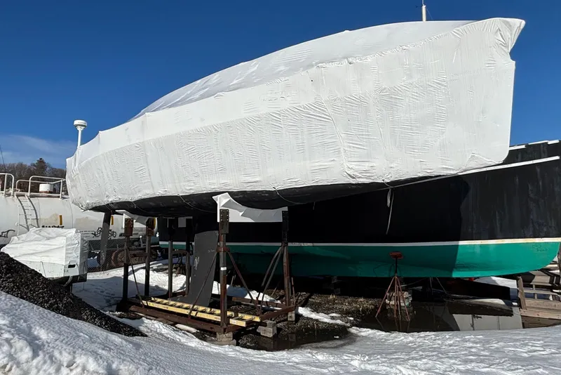 Slide: The Image of Covered 1995 Tripp 47 sailboat in winter storage, surrounded by snow and clear blue sky. - 62