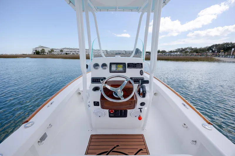 Slide: The Image of 2017 Chaos 21 Tarpon Bay boat interior with steering wheel and controls on calm water. - 21