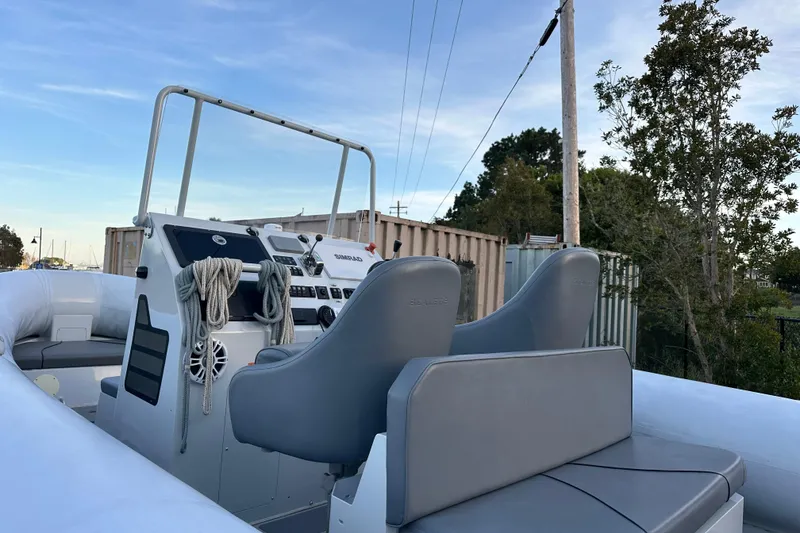 Slide: The Image of 2020 Sealegs 9m Amphibious RIB with dual seats and control panel, docked outdoors. - 16