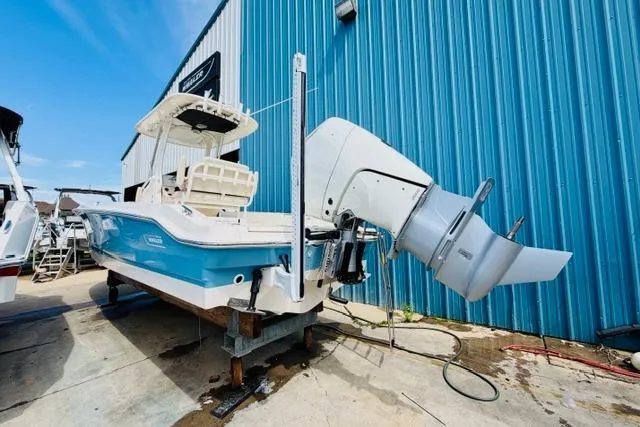 Slide: The Image of 2026 Boston Whaler 250 Dauntless boat docked near blue building. - 2