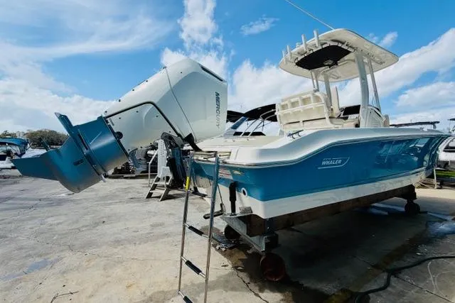 Slide: The Image of 2026 Boston Whaler 250 Dauntless boat with outboard motor, docked under a clear blue sky. - 3