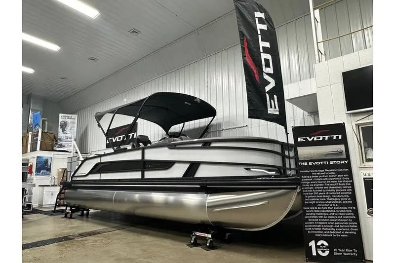 The Image of 2026 Evotti 723CS pontoon boat displayed indoors with promotional banners. - 1