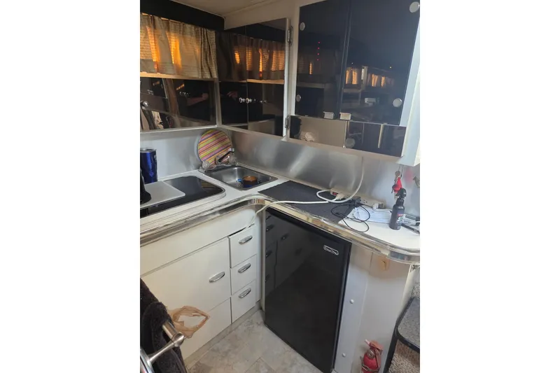 Slide: The Image of 1988 Wellcraft 3200 St. Tropez boat kitchen with sink, stove, and storage cabinets. - 10