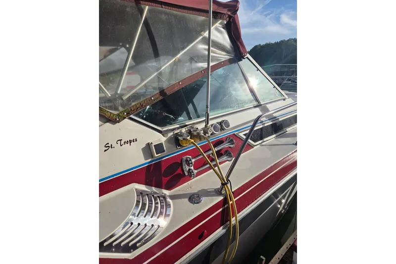Slide: The Image of 1988 Wellcraft 3200 St. Tropez boat with red and white detailing, docked in sunlight. - 2