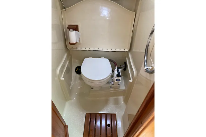 Slide: The Image of 1992 Hunter 33.5 yacht bathroom with toilet, shower, and wooden floor mat. - 12