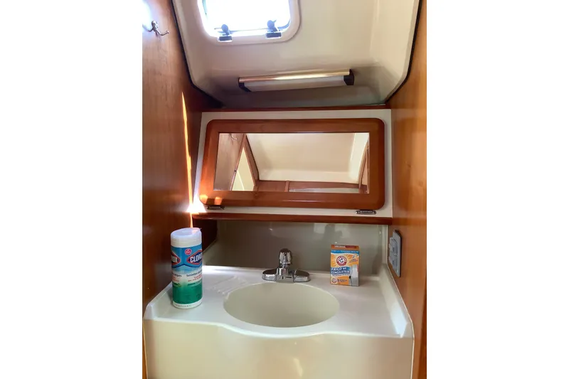 Slide: The Image of 1992 Hunter 33.5 yacht bathroom with sink, mirror, and cleaning supplies. - 13