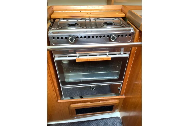 Slide: The Image of 1992 Hunter 33.5 yacht kitchen stove and oven, featuring a compact design and wooden accents. - 16