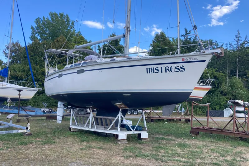 Slide: The Image of 1992 Hunter 33.5 sailboat named "Mistress" on dry dock, surrounded by trees and blue sky. - 29