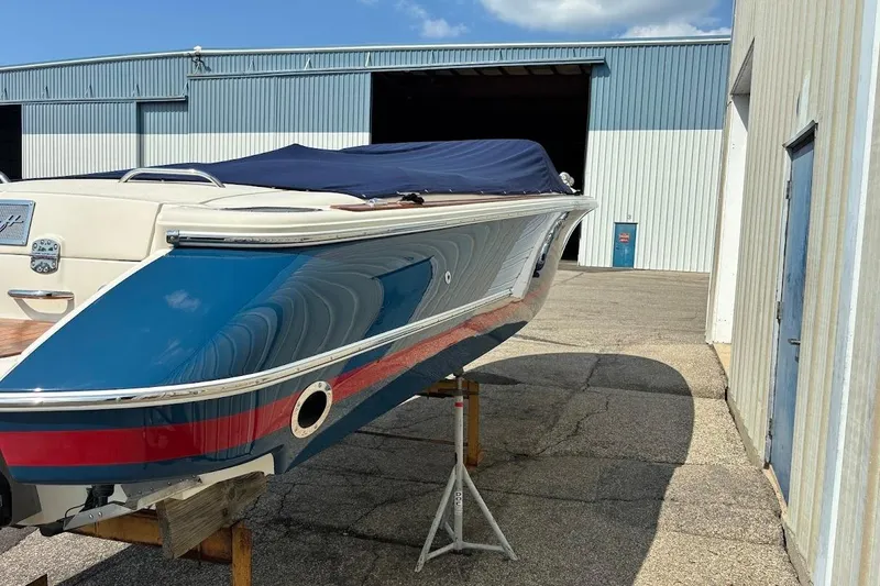 Slide: The Image of 2007 Chris-Craft Corsair 25 boat with blue cover, parked outside a warehouse. - 11