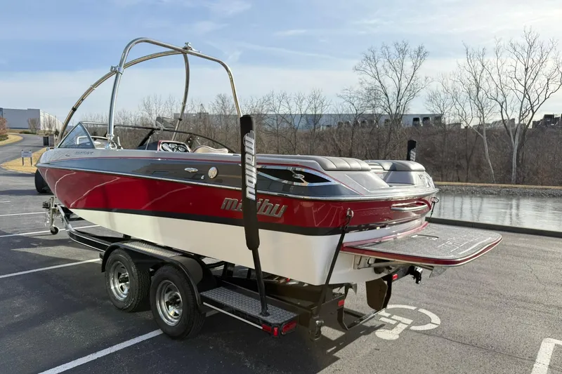 Slide: The Image of 2008 Malibu Sunscape 23 LSV boat on trailer, parked near a lake. - 5