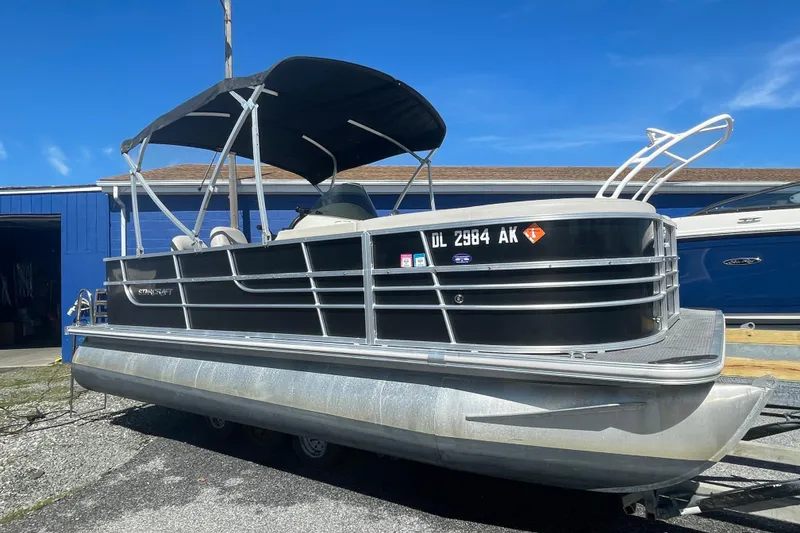 Slide: The Image of 2016 Starcraft EX 20 CF pontoon boat with canopy on trailer, parked outdoors. - 13