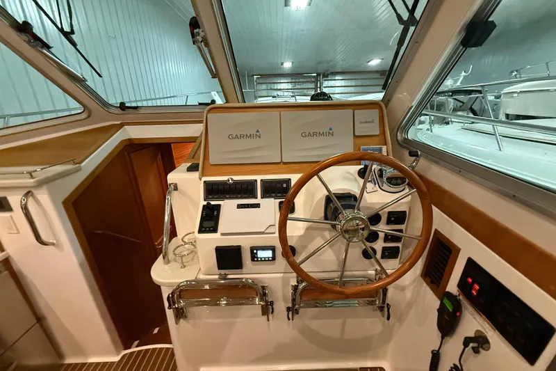 Slide: The Image of 2017 Back Cove 37 helm with Garmin navigation, wooden steering wheel, and control panel. - 25
