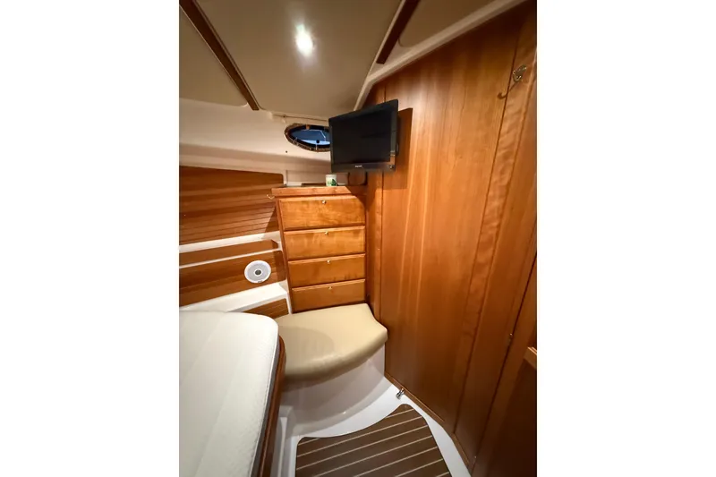 Slide: The Image of 2017 Back Cove 37 interior cabin with wood paneling, drawers, and a mounted TV. - 36