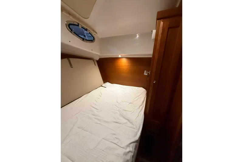 Slide: The Image of 2017 Back Cove 37 cabin interior with bed, wooden paneling, and porthole window. - 41
