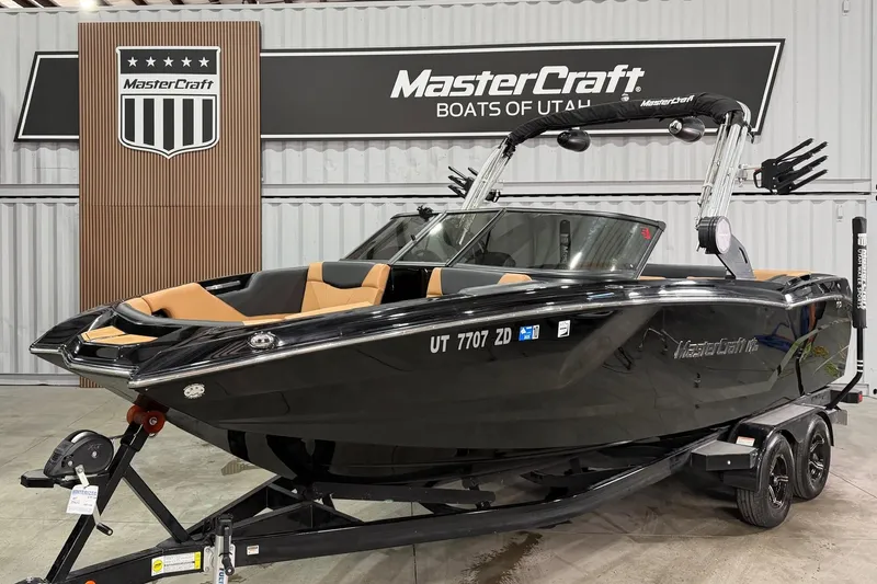The Image of 2022 MasterCraft NXT24 boat in showroom, black exterior, on trailer. - 1