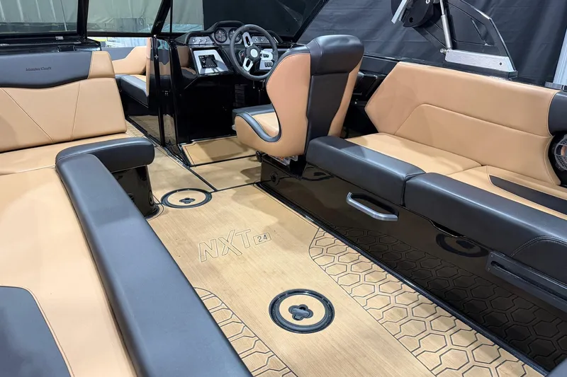 Slide: The Image of 2022 MasterCraft NXT24 boat interior with tan and black seating, modern dashboard, and stylish flooring. - 10
