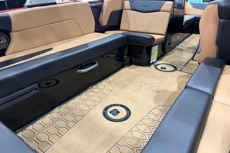 Slide: The Image of 2022 MasterCraft NXT24 boat interior with tan and black seating, hexagonal floor design. - 11