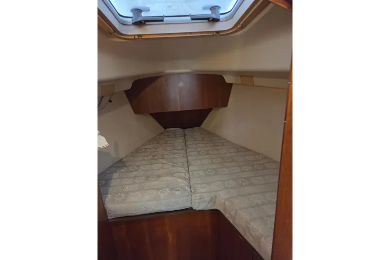 Slide: The Image of 2003 Hunter 326 boat cabin interior with a cozy bed and overhead hatch. - 13