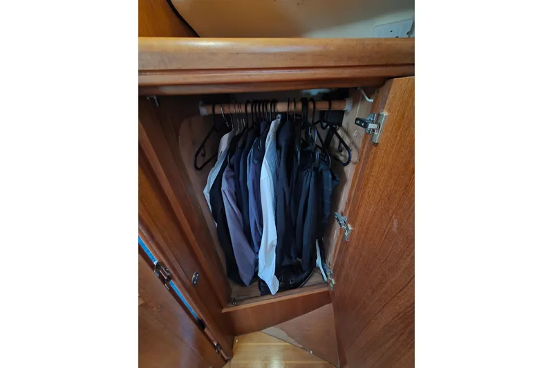 Slide: The Image of Wooden closet with hanging clothes inside a 2003 Hunter 326 model. - 15