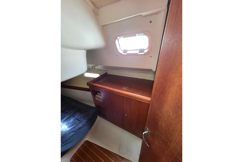 Slide: The Image of 2003 Hunter 326 yacht cabin interior with wooden cabinetry and small window. - 17