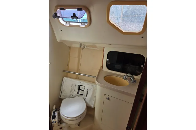 Slide: The Image of Compact bathroom in 2003 Hunter 326 sailboat with toilet, sink, and porthole window. - 18