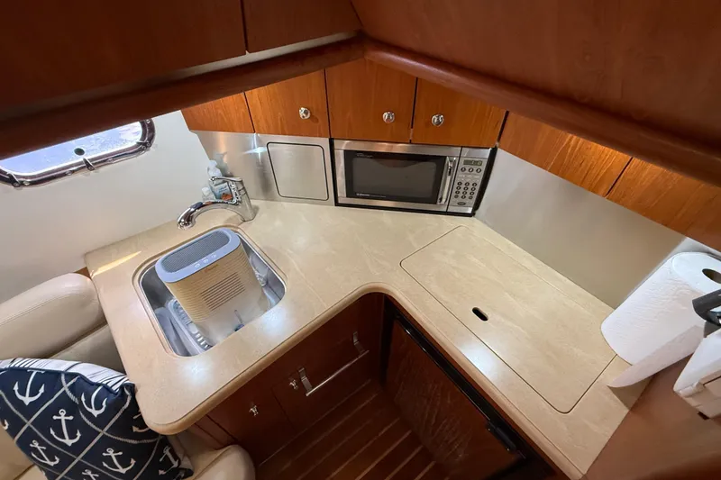 Slide: The Image of 2004 Tiara Yachts 3600 Sovran galley with sink, microwave, and wooden cabinetry. - 40