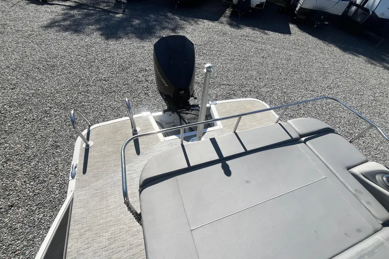 Slide: The Image of 2022 Bennington 23LT boat with outboard motor and spacious deck, parked on gravel. - 11