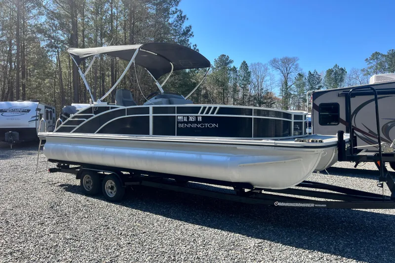 Slide: The Image of 2022 Bennington 23LT pontoon boat on trailer, parked outdoors near RVs and trees. - 4