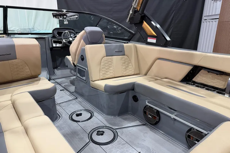 Slide: The Image of 2022 MasterCraft X26 boat interior with beige and gray seating, modern design, and spacious layout. - 12