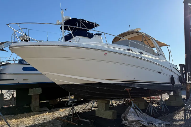 The Image of 2003 Sea Ray 300 Sundancer boat on dry dock, side view, clear sky background. - 0