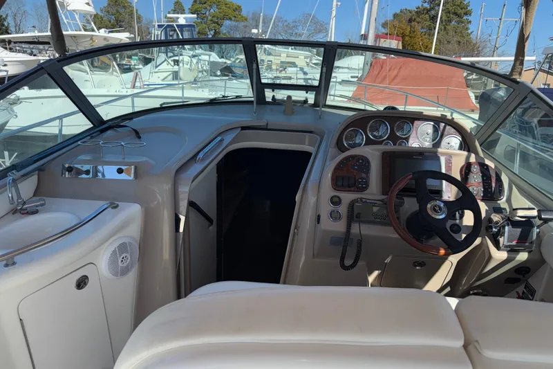 Slide: The Image of 2003 Sea Ray 300 Sundancer cockpit with steering wheel and control panel, docked at marina. - 11