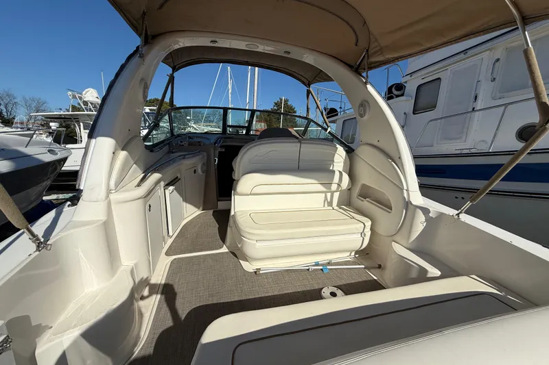 Slide: The Image of 2003 Sea Ray 300 Sundancer boat interior with seating and helm, docked in marina. - 12