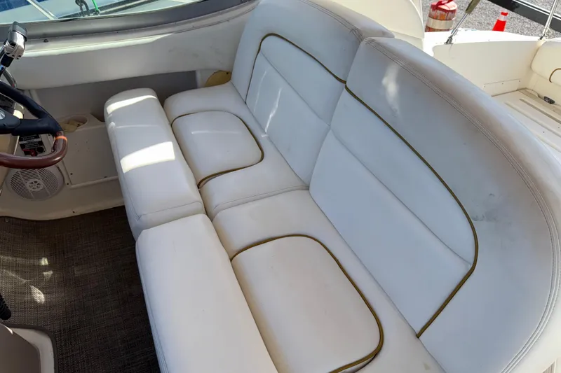 Slide: The Image of 2003 Sea Ray 300 Sundancer interior with white cushioned seating and steering wheel. - 14