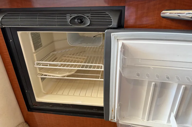 Slide: The Image of Open refrigerator inside 2003 Sea Ray 300 Sundancer boat, showing empty shelves. - 20