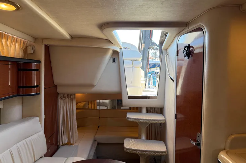 Slide: The Image of Interior of 2003 Sea Ray 300 Sundancer yacht, featuring elegant seating and wooden cabinetry. - 21
