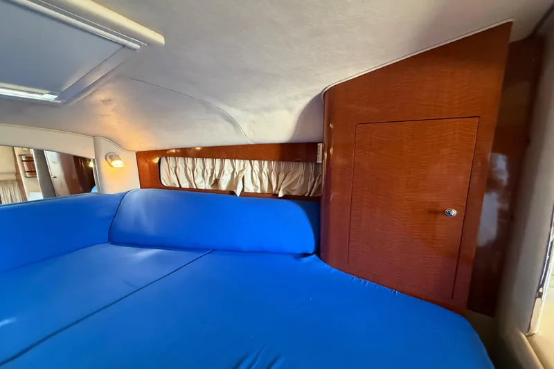 Slide: The Image of Interior cabin of 2003 Sea Ray 300 Sundancer with blue upholstery and wooden paneling. - 32