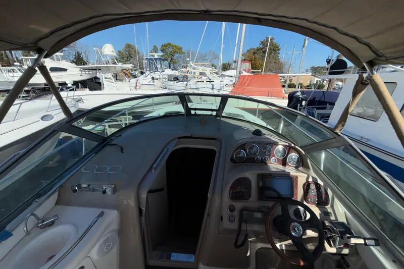 Slide: The Image of 2003 Sea Ray 300 Sundancer cockpit with steering wheel, dashboard, and marina view. - 8