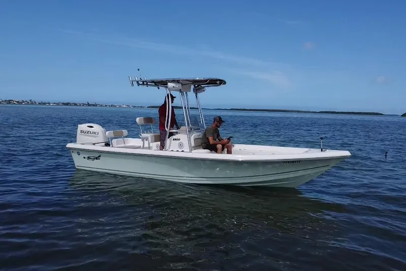Slide: The Image of 2021 Bulls Bay 2200 boat on calm water with a person seated, clear sky background. - 18