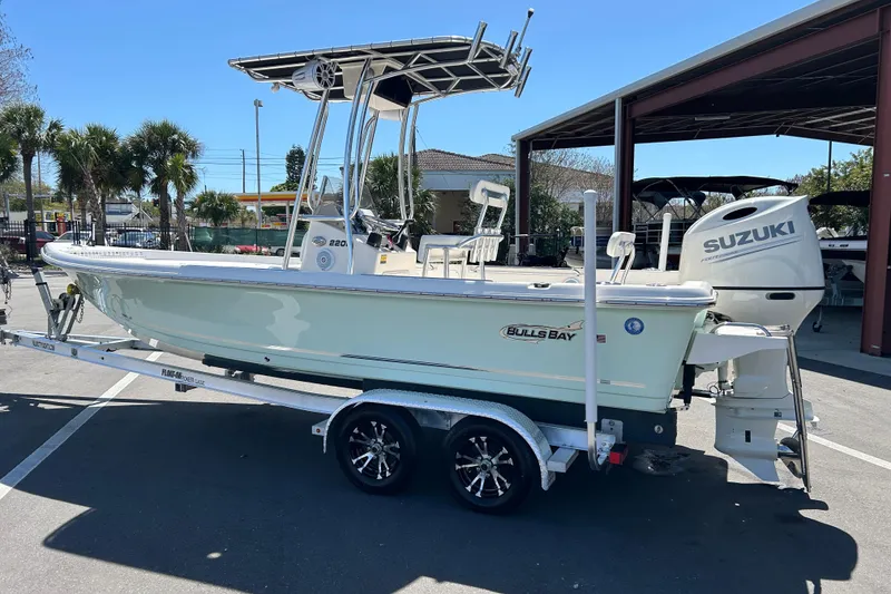 Slide: The Image of 2021 Bulls Bay 2200 boat on trailer with Suzuki outboard motor, parked outdoors. - 4